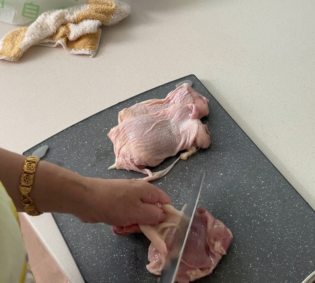 Chicken thighs being prepped by removing the skin and dicing the meat.