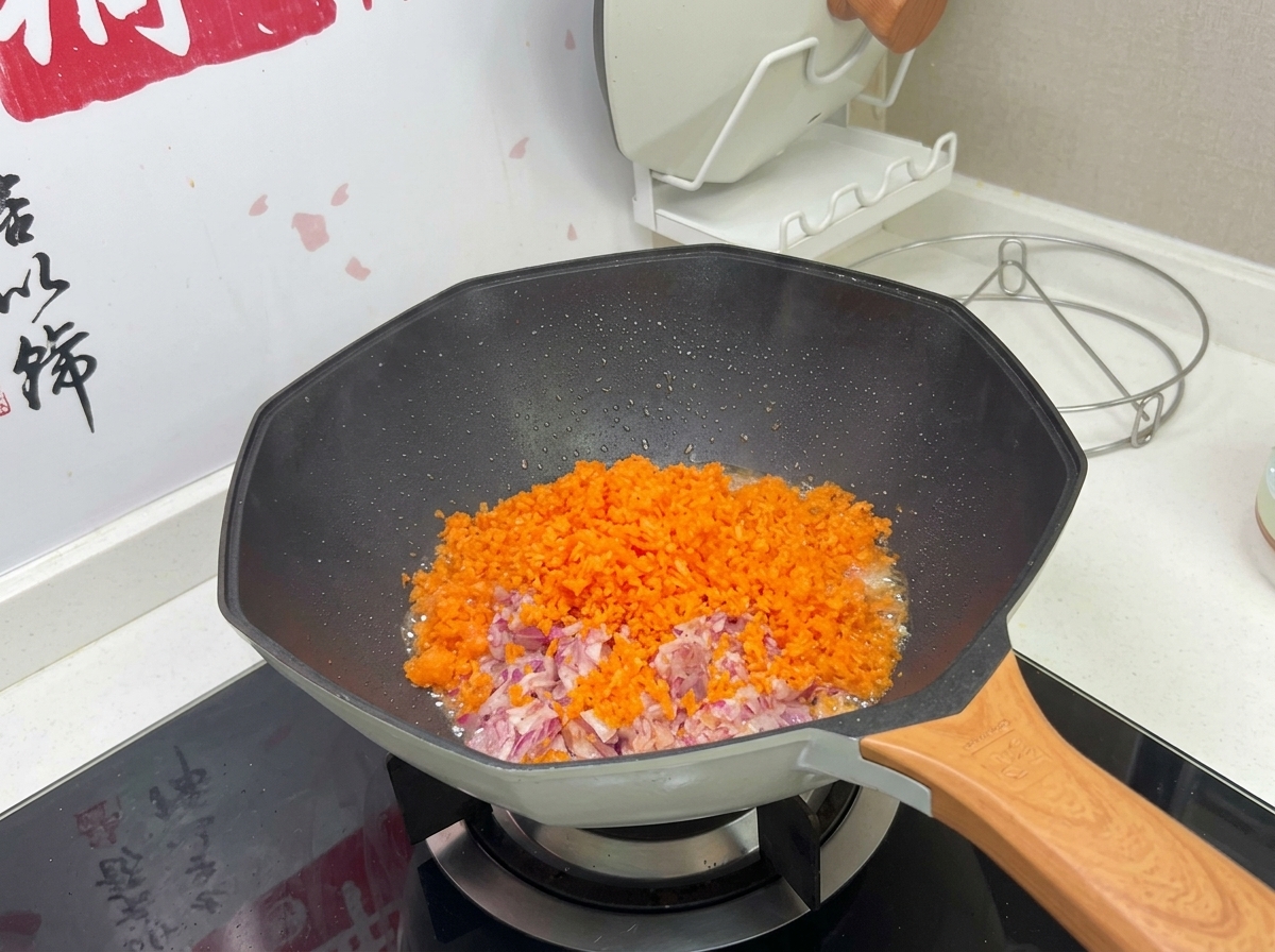 A colorful mound of finely diced orange carrots and purple onions cooking in a hot wok.