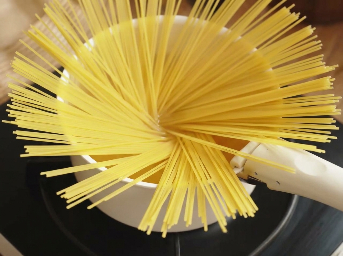 A bunch of dry spaghetti being dropped into a pot of boiling water.