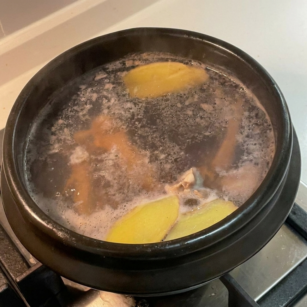 A black stone pot covered with a lid, simmering on a stovetop.
