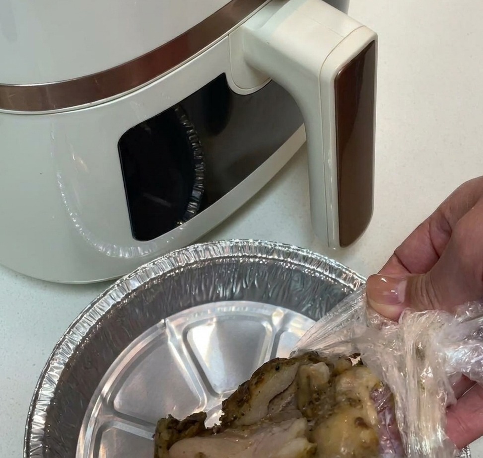 Pre-seasoned chicken thigh meat being placed into an aluminum-lined air fryer basket.