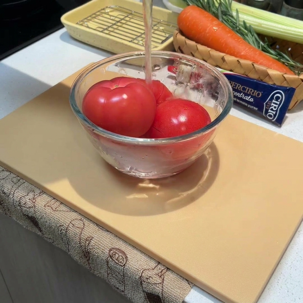 Close-up of whole tomatoes in a bowl being covered with hot water.