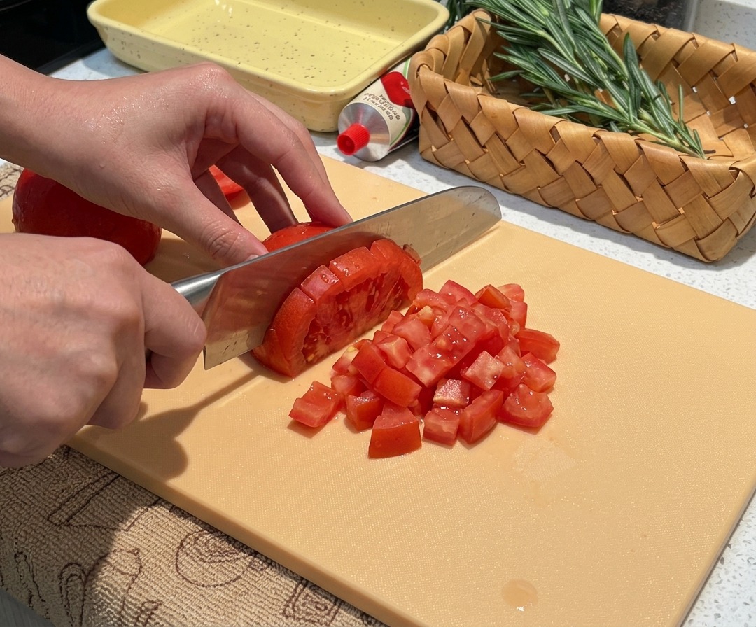 Fresh peeled tomatoes being diced into small, uniform pieces.