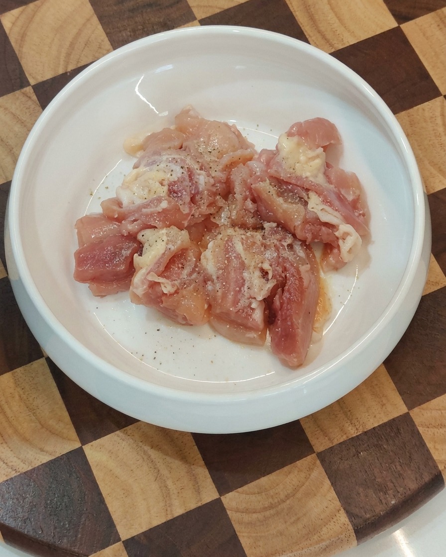 Bowl containing seasoned raw chicken pieces ready for the pan.