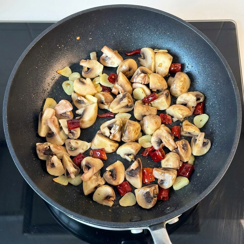 Butter and dried parsley being added to the pan of sautéed mushrooms.