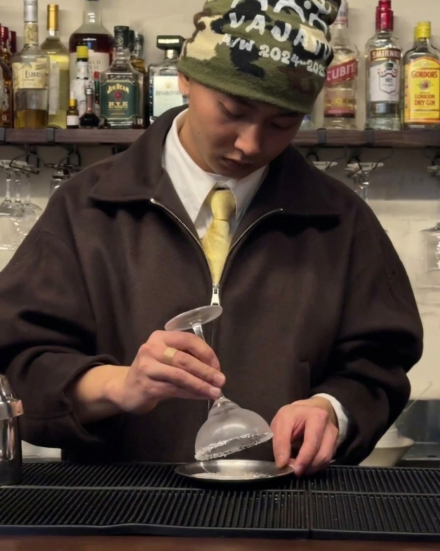 A chilled coupe glass being rimmed with salt on a small saucer.