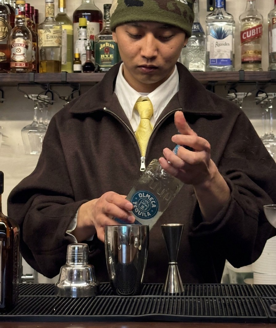 Tequila being measured into a jigger and poured into a cocktail shaker.
