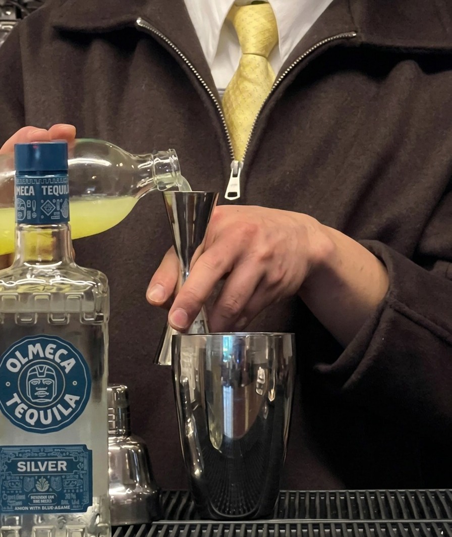 Fresh lime juice being poured into a jigger over a cocktail shaker.