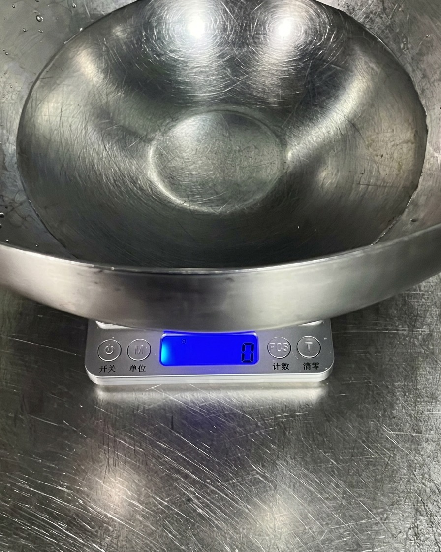 A large stainless steel bowl filled with clear water resting on a digital kitchen scale.