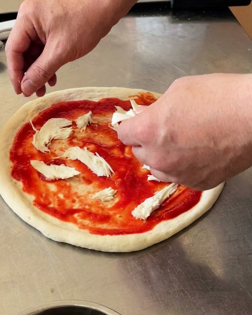 Pizza topped with pieces of white buffalo mozzarella and fresh green basil leaves.