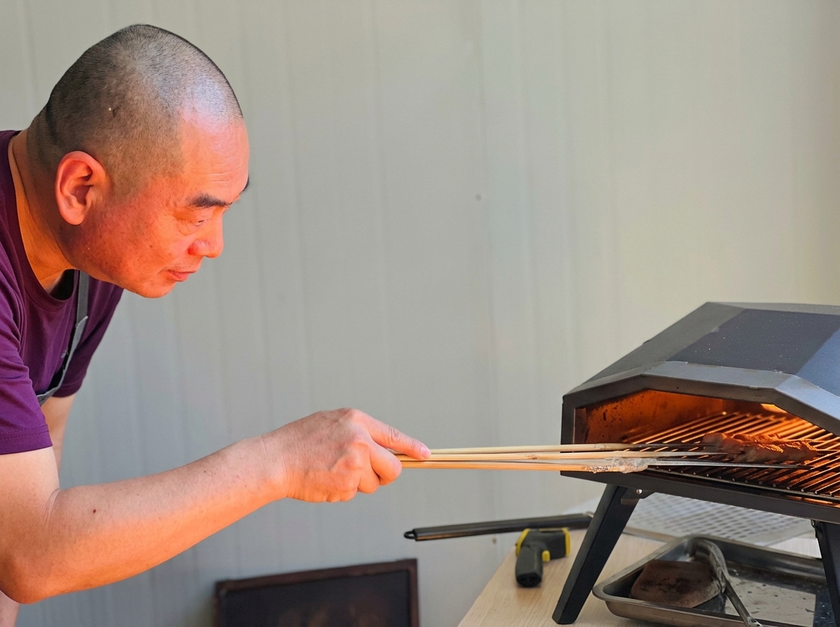 A pizza crust beginning to puff and brown inside the oven, being rotated by a professional turning peel.