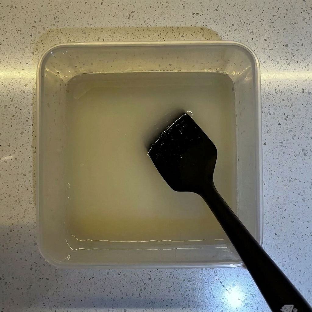 Flour being poured into a clear container holding the prepared yeast water mixture.