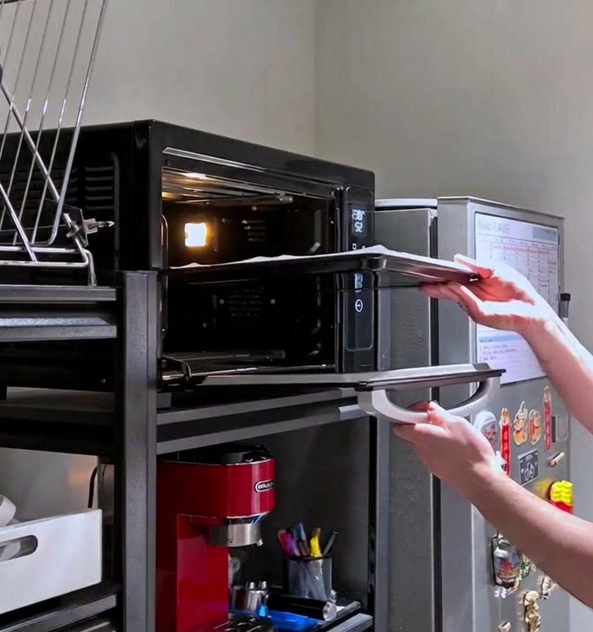 A person sliding a baking tray with raw, pricked pizza dough into a glowing hot home oven.