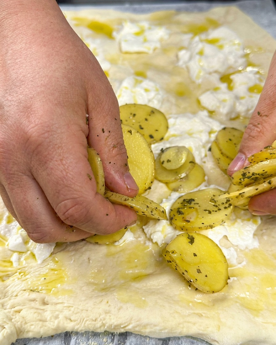 Thin potato slices arranged on the creamy cheese base, topped with fresh herbs.