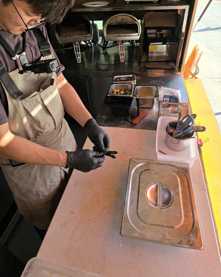 White sauce being spread evenly over the surface of the pizza dough.