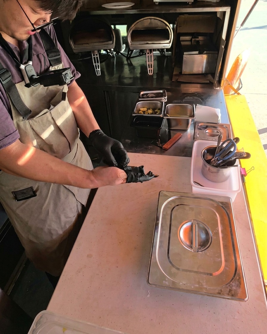 A freshly topped pizza being transferred with a wooden peel into a hot, glowing pizza oven.