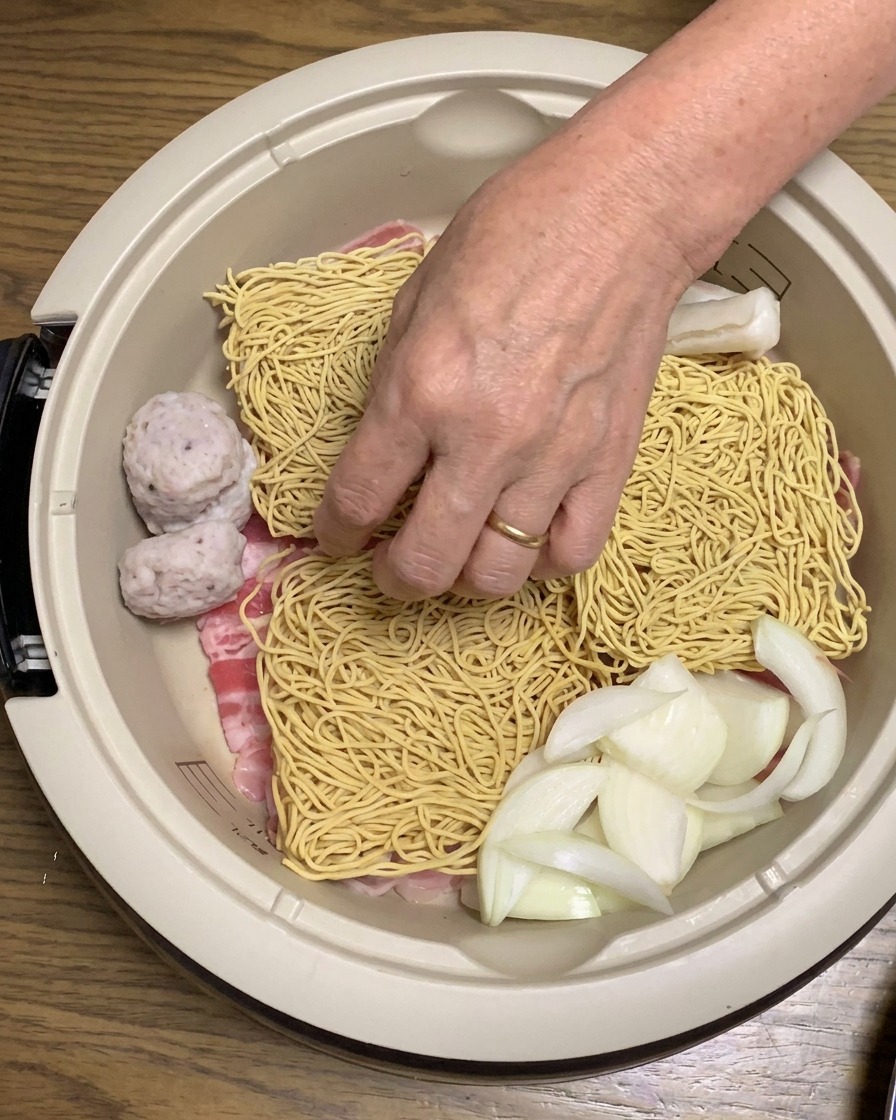 Rice cakes and golden fried tofu being added to the assembled ingredients in the pot.