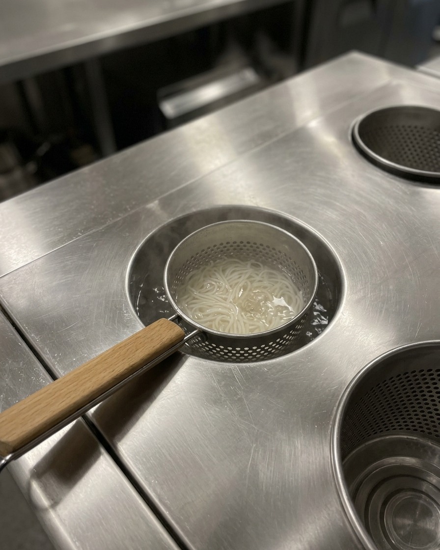 Cooked ramen noodles sitting in a serving bowl, being prepared for the addition of the hot broth.