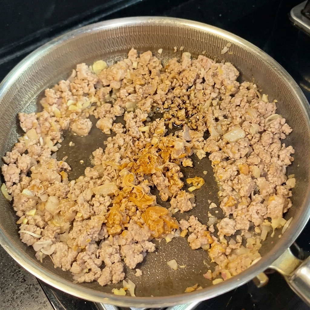 Soy milk and soy sauce being added to the pan to form a creamy sauce.