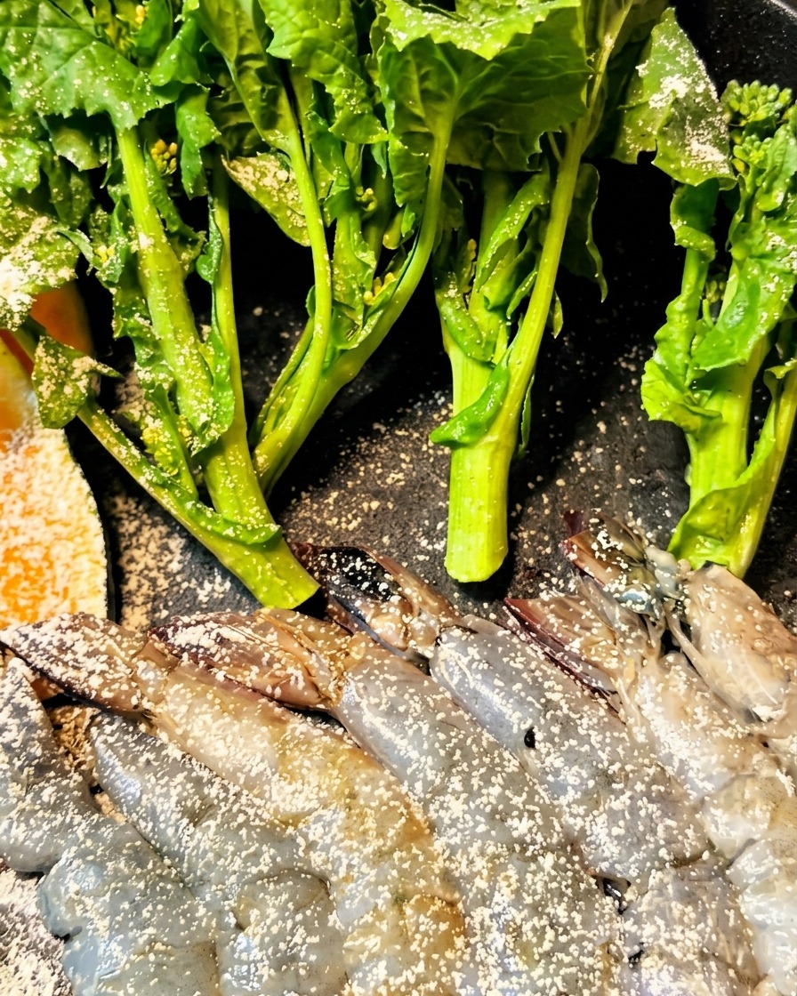 Shrimp and eggplant being coated in batter and placed into a fryer.