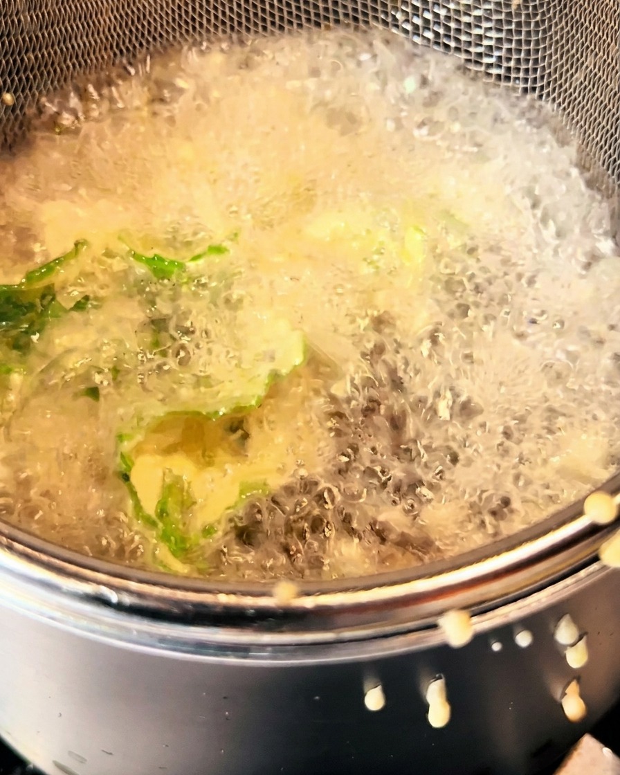 Battered greens frying in hot oil, golden and crispy.