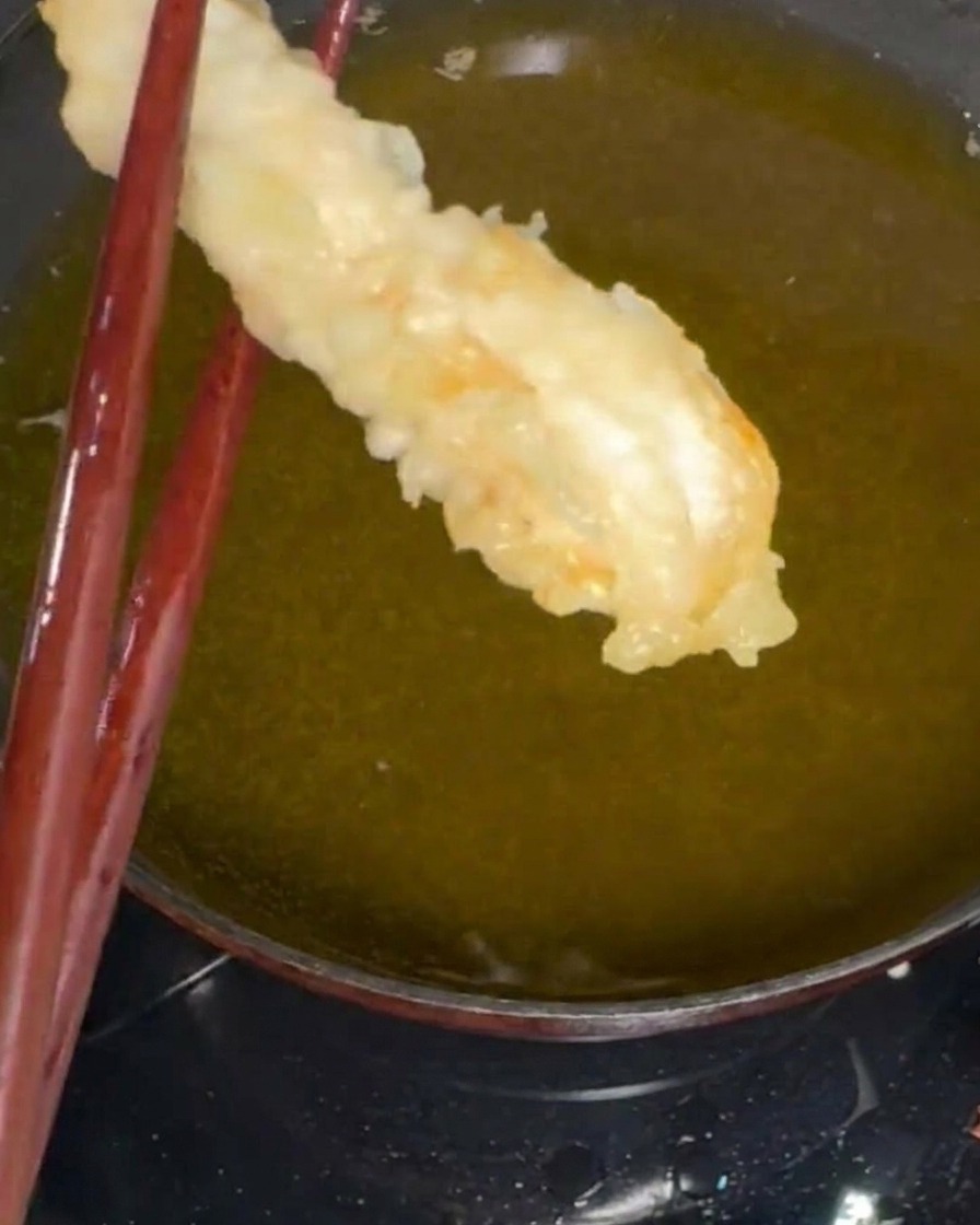 Shrimp being coated in batter after a light dusting of dry flour.