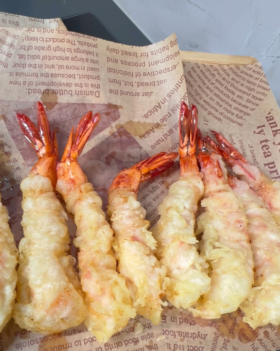 Battered shrimp frying in hot oil with crispy spikes forming on the surface.