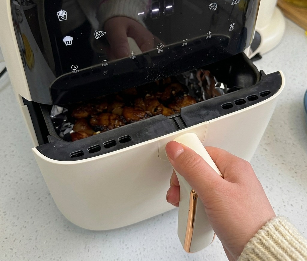 The air fryer basket partially pulled out, revealing the pork belly inside which is starting to brown and sizzle.
