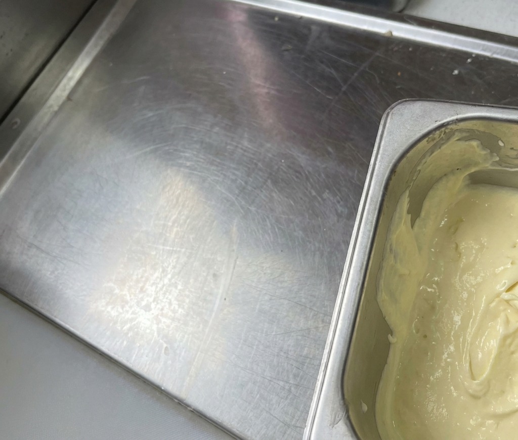 A metal container filled with a thick, pale yellow blended sauce that has a smooth, creamy appearance.