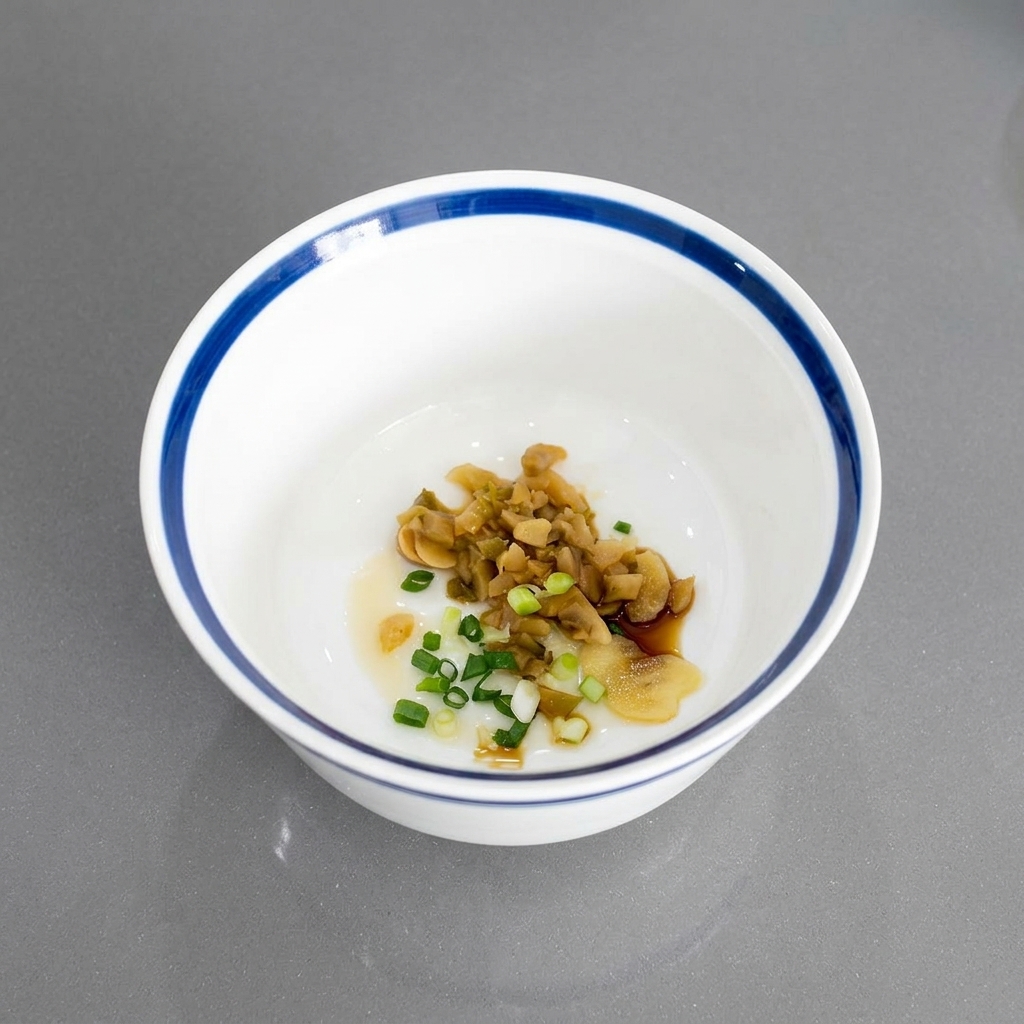 Chopped green onions mixed with pickled vegetables and garlic at the bottom of a white ceramic bowl.