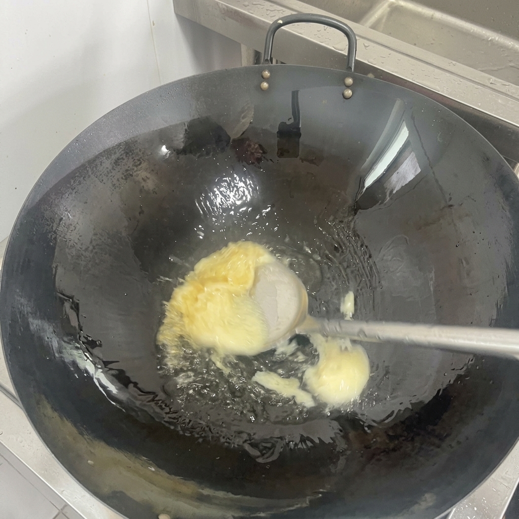 A solid piece of white lard melting into clear oil at the bottom of a seasoned black wok.