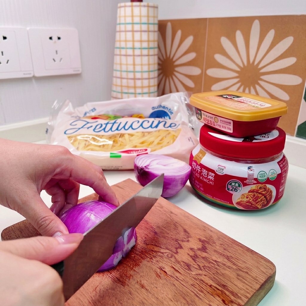 Close-up of hands using a knife to dice a purple red onion into small bits on a wooden board.