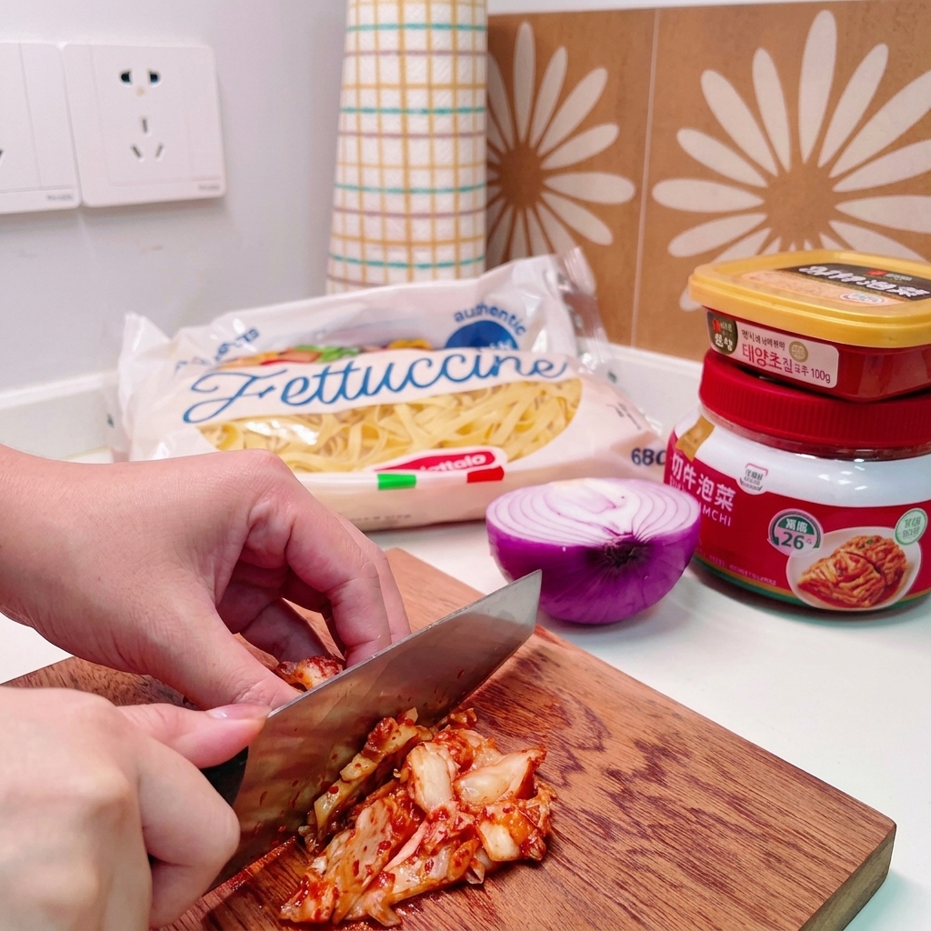 A knife chopping through a pile of cabbage kimchi on a wooden cutting board.