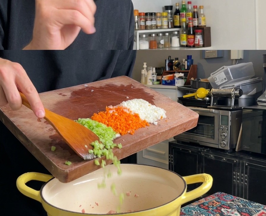 A wooden spoon scraping finely diced carrots, celery, and onions off a cutting board into a yellow cooking pot.