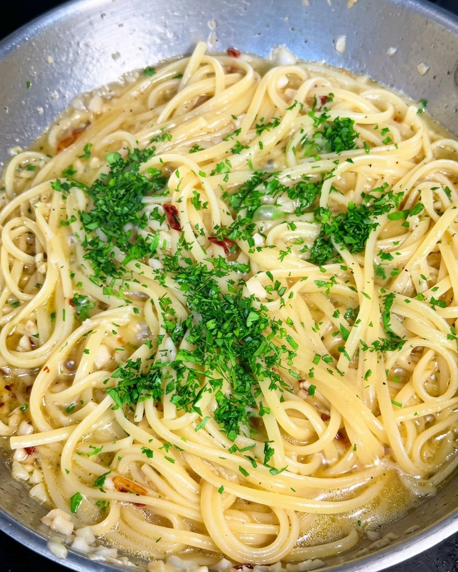 Bright green chopped parsley scattered over a pan of garlic olive oil pasta.