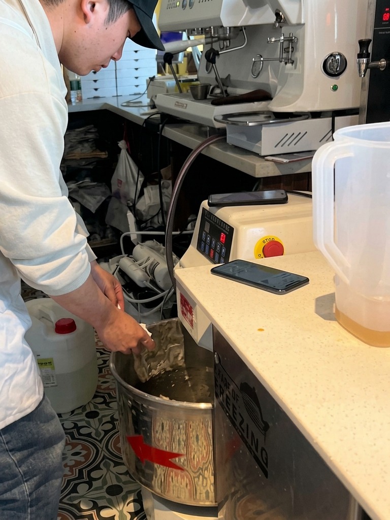A baker adding yeast into a large commercial mixer where the dough is starting to clump together.