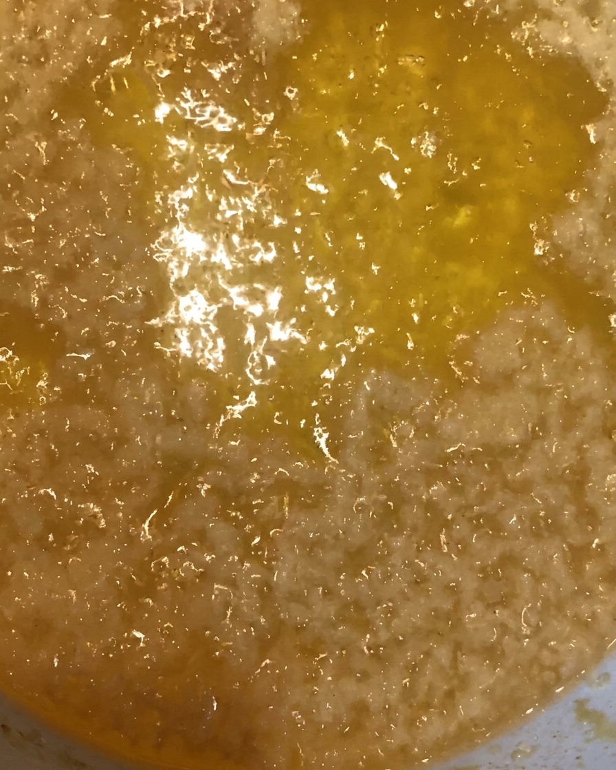 Golden crispy batter crumbs being scooped out of hot oil using a metal strainer.