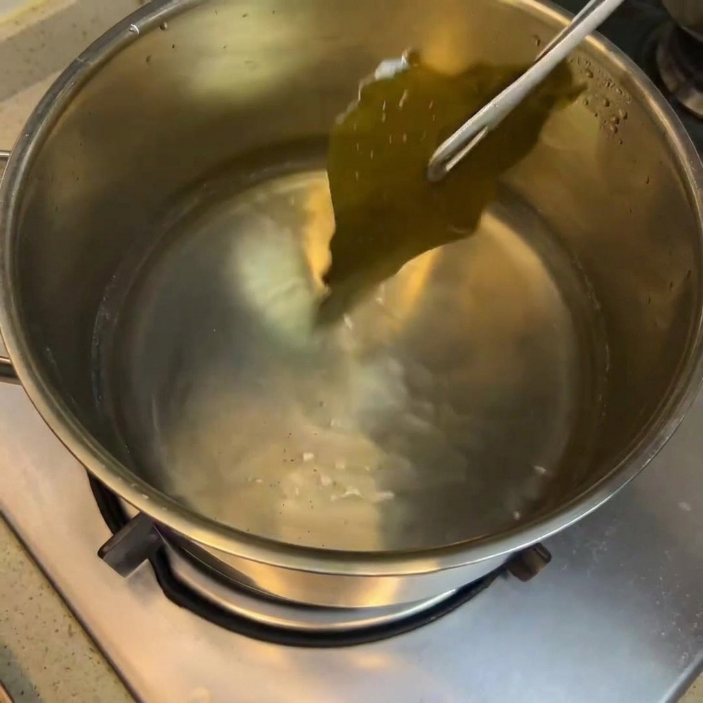 Soy sauce, rice wine, and sugar being stirred into the pot with the kelp stock.