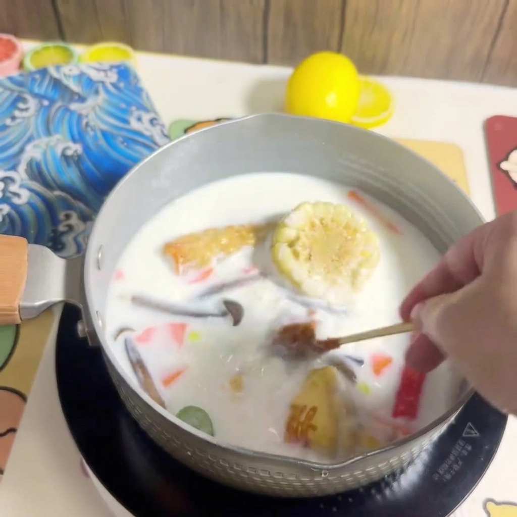 A block of ramen noodles being placed into the pot of boiling broth and ingredients.