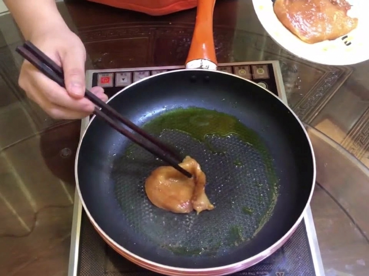 Marinated meat pieces browning in a pan with a little oil.