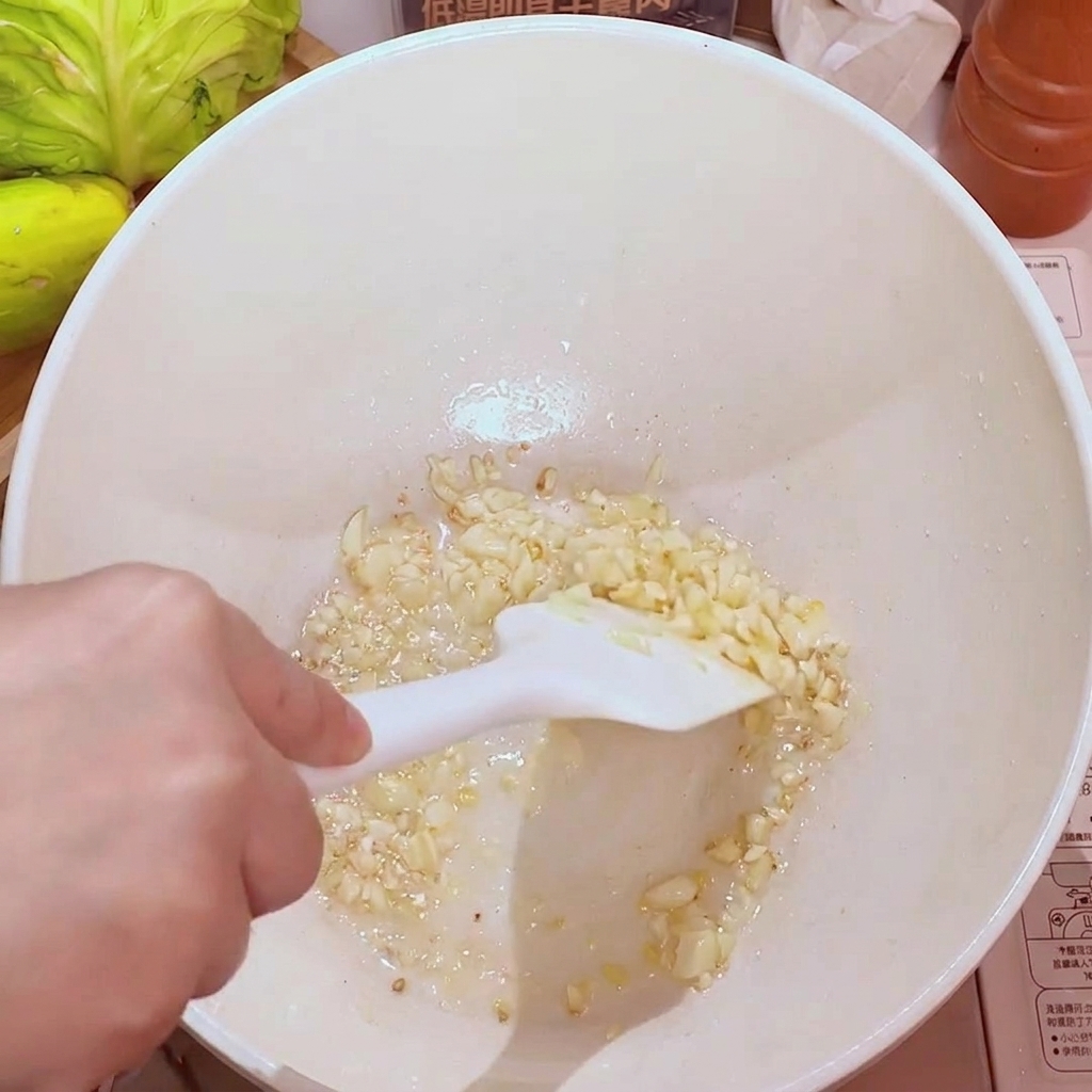 Minced garlic sizzling in a pan with oil, turning golden and aromatic.