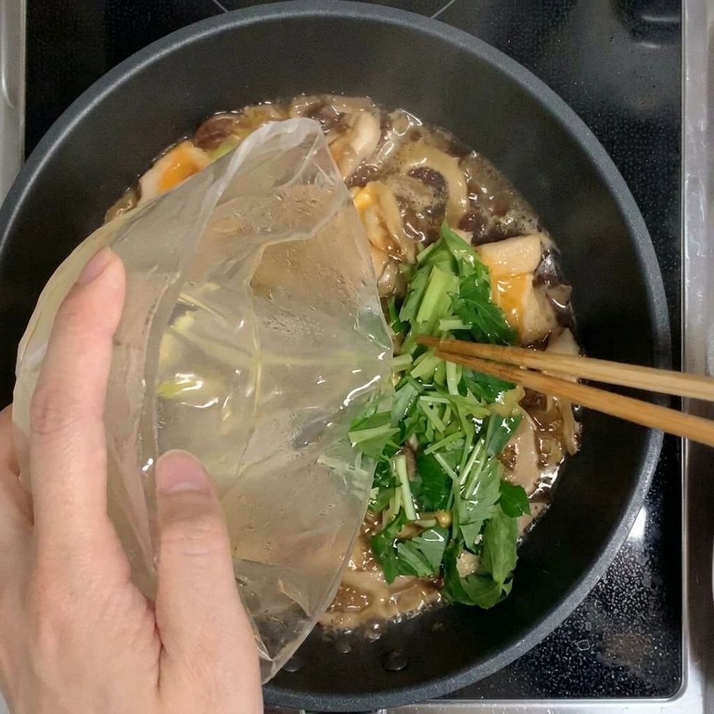 The final one-third of the egg and mitsuba mixture being added to the pan.