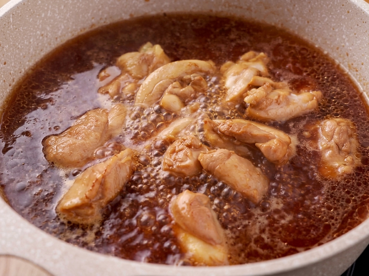 Foam being skimmed off the surface of a boiling chicken and teriyaki sauce mixture.