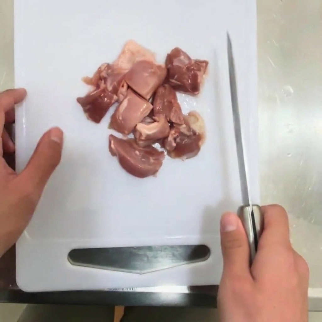 An onion being sliced into thin strips on a cutting board.