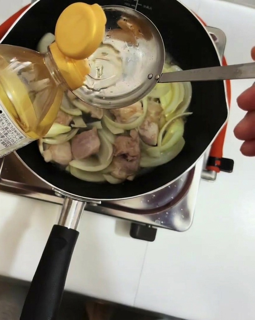 Mirin being added to the pan using a metal ladle.