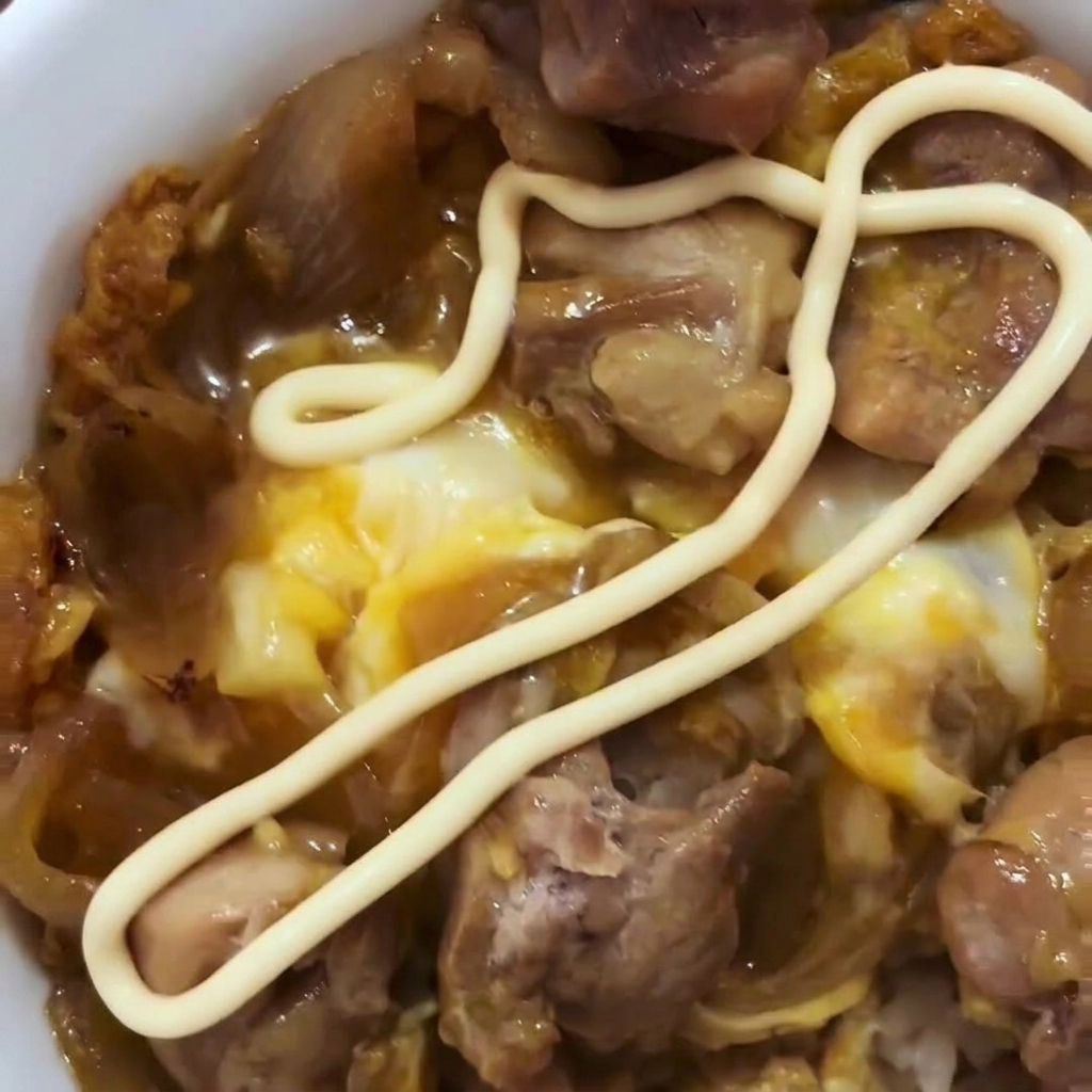 Beaten eggs being poured over the cooked chicken and onions in a skillet.