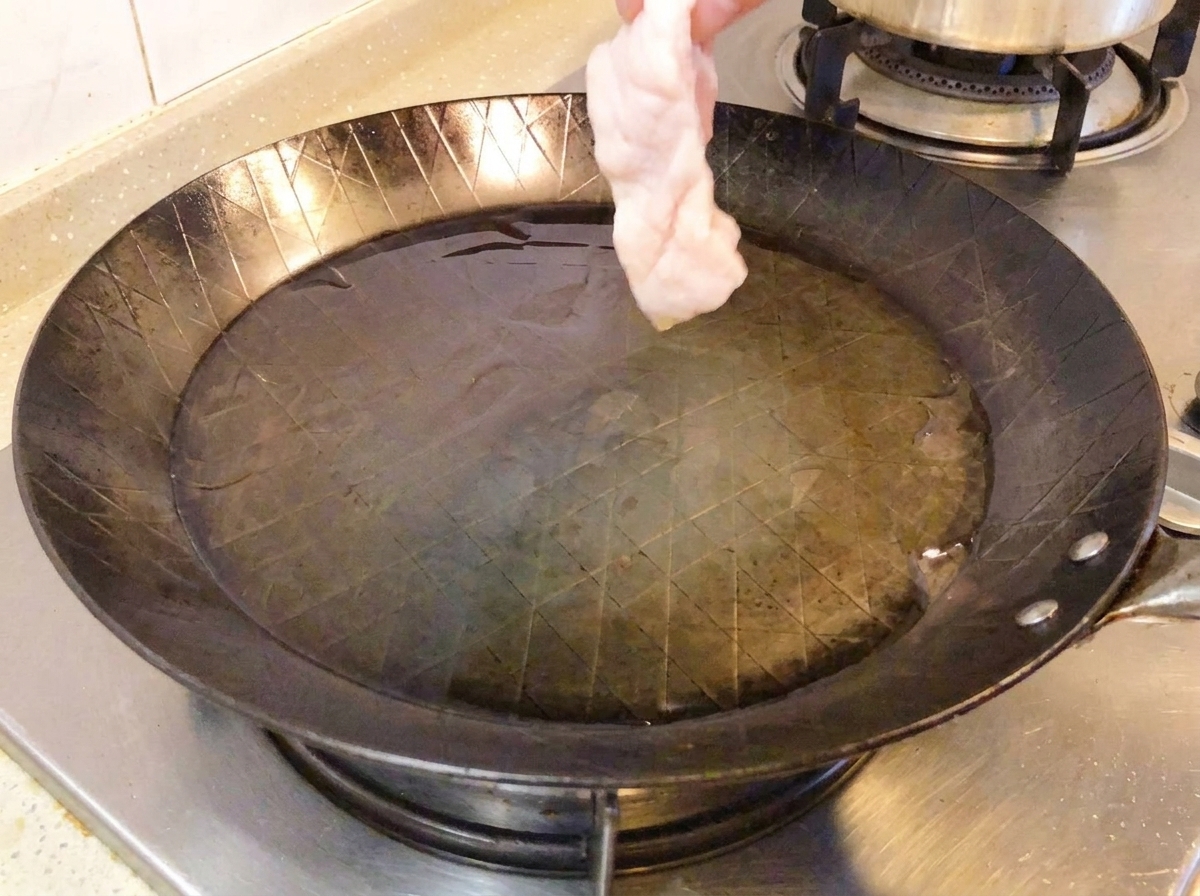 Raw chicken leg skin-side down in a hot pan.