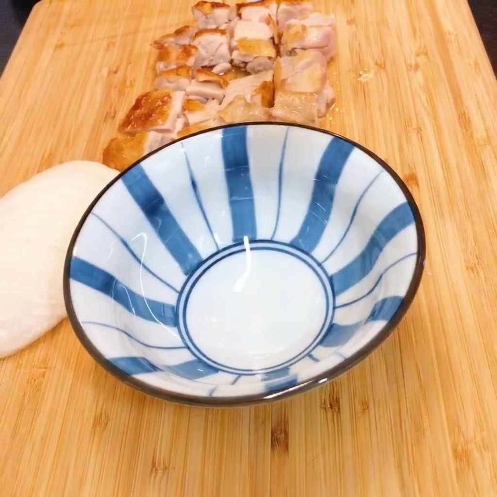 Mirin and soy sauce being mixed in a blue and white striped bowl.