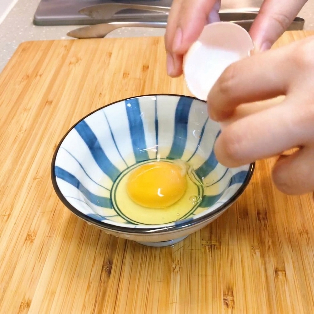 Two raw eggs being gently stirred with chopsticks in a blue and white striped ceramic bowl.