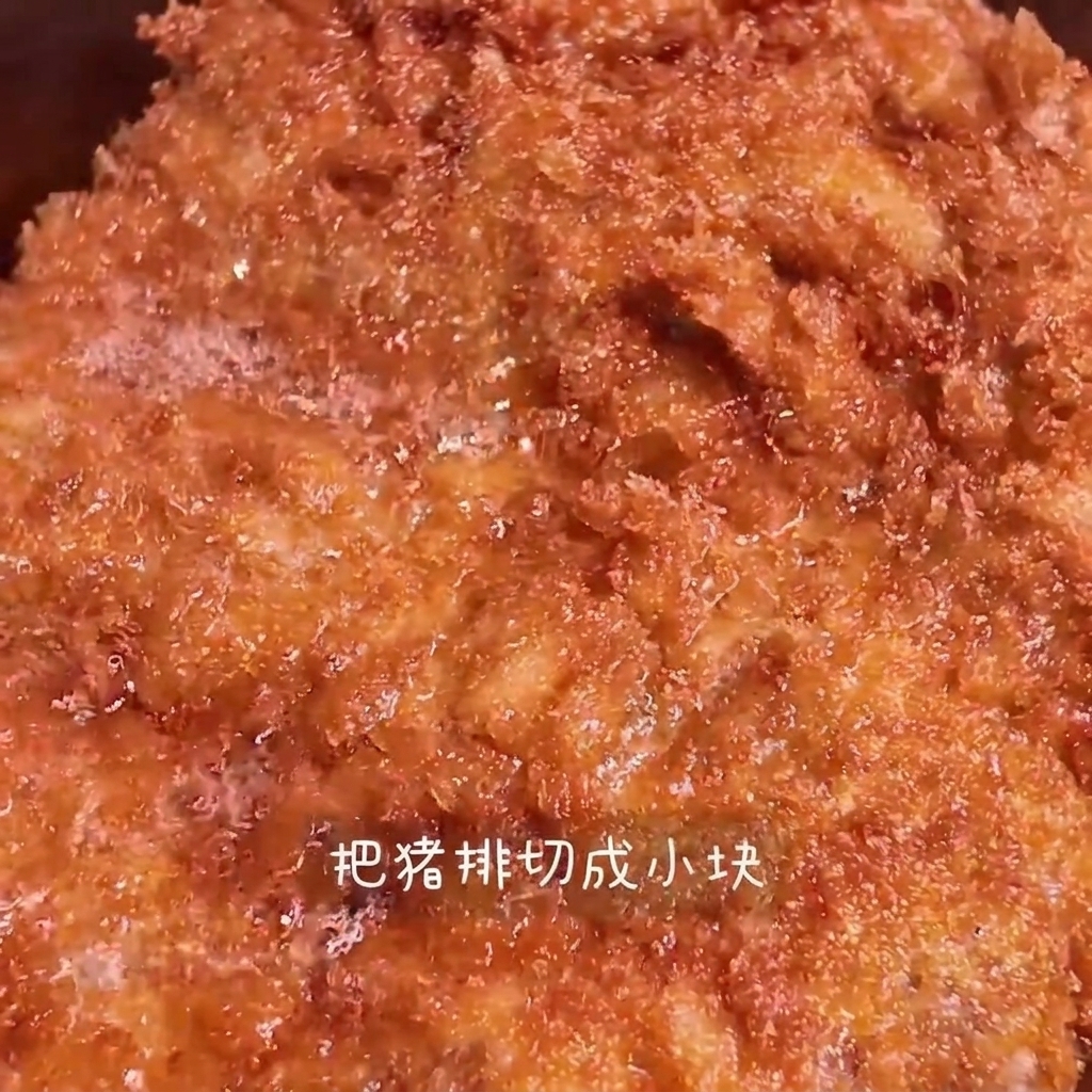 A crispy, golden-brown fried pork chop being sliced into strips on a wooden cutting board.
